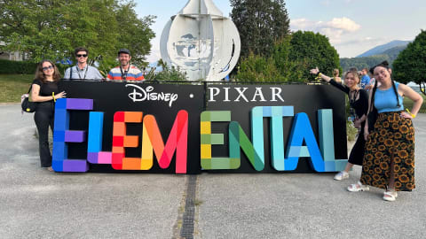 一张五个人在一个写着迪士尼皮克斯元素的牌子前微笑的照片