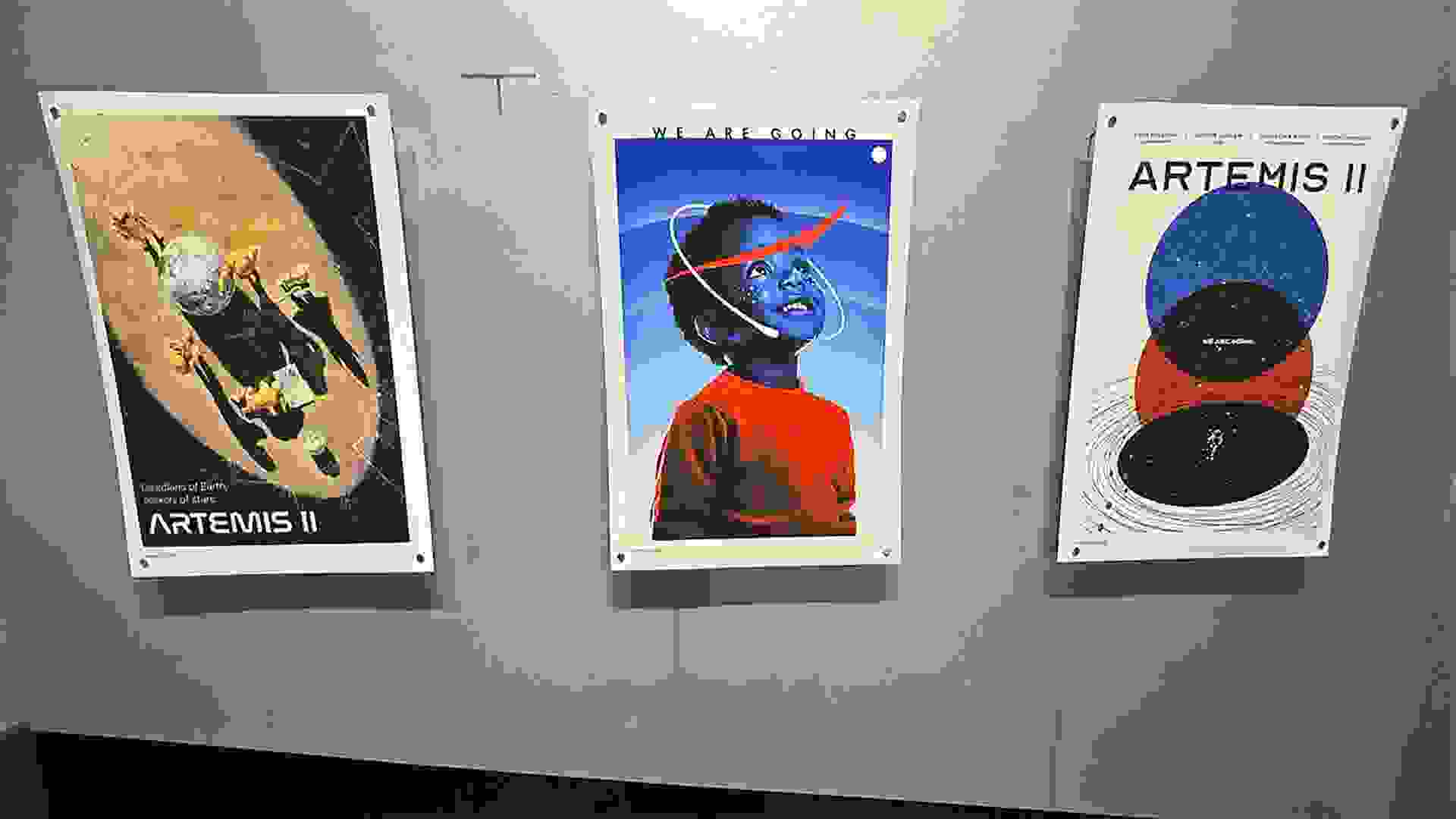 Three ARTEMIS II posters designed by SVA students on a gray wall.