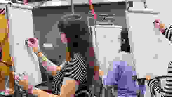 Students sketching on pads while standing up.