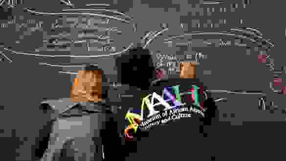 Diverse Students writing on a chalk board