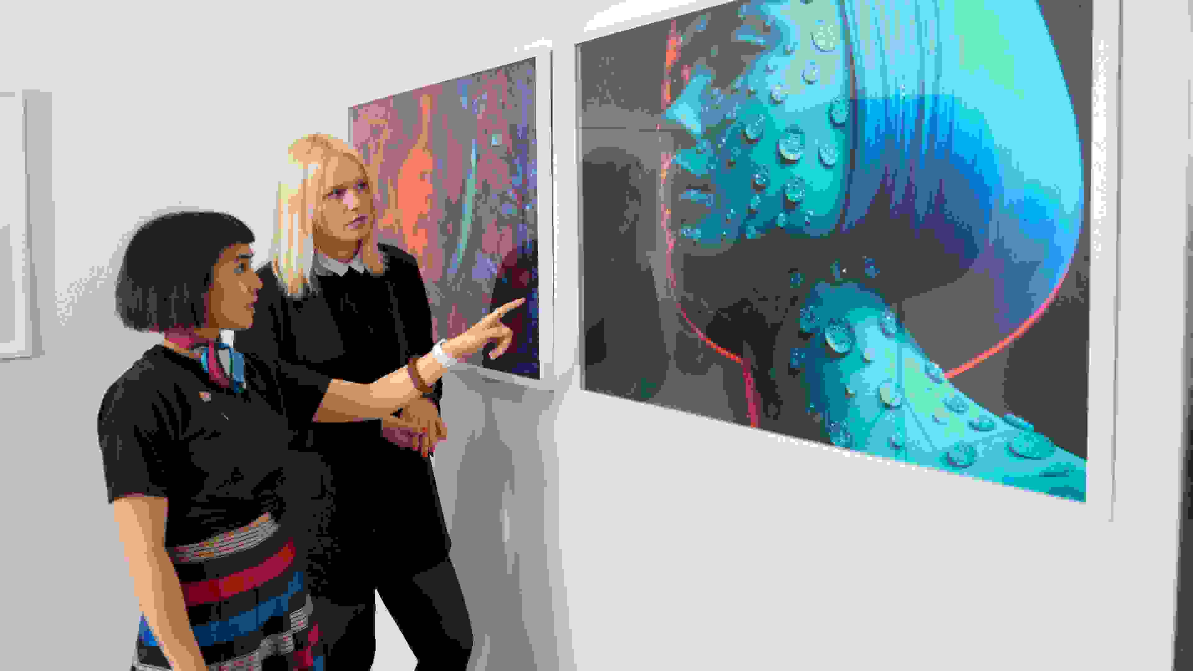 Two students discussing large framed fashion photograph