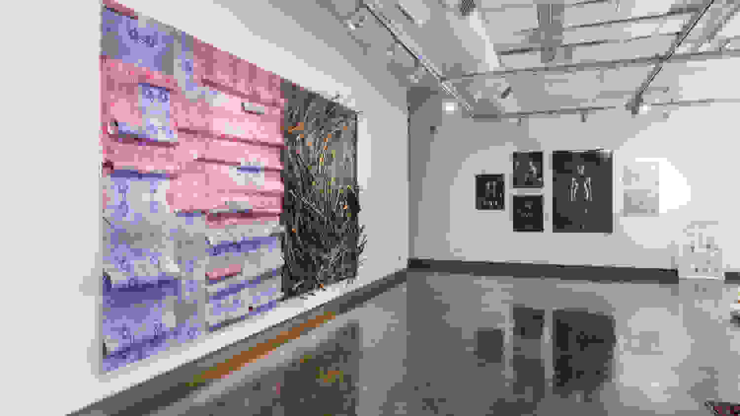 Installation view of “Once Upon a Time…,” curated by department chair Suzanne Anker at the SVA Chelsea Gallery, 601 West 26th Street. Large artwork made with tree branches and purble screenprinting geometrical patterns on the left and black and white photographs of a women of color painted in black on the right.