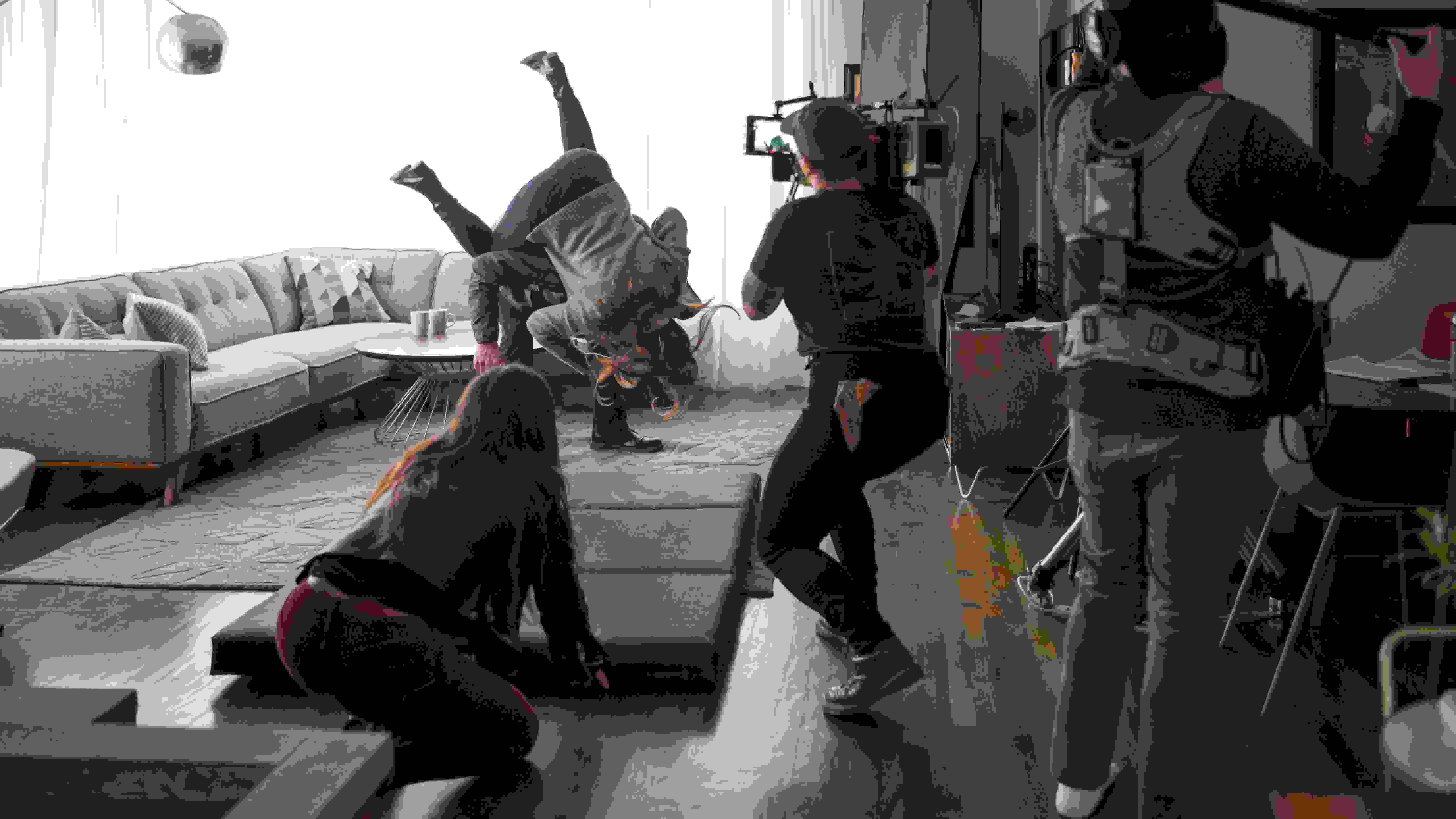 A camera person crouches to capture a fight scene taking place in front of a window.