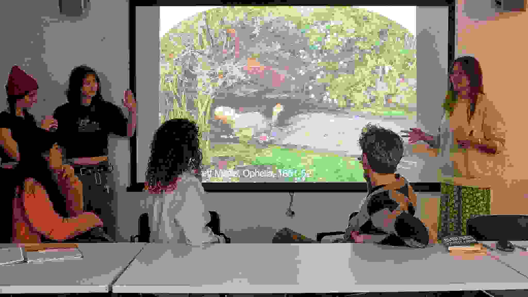 Image of students in a seminar style classroom discussing a work of art during class.