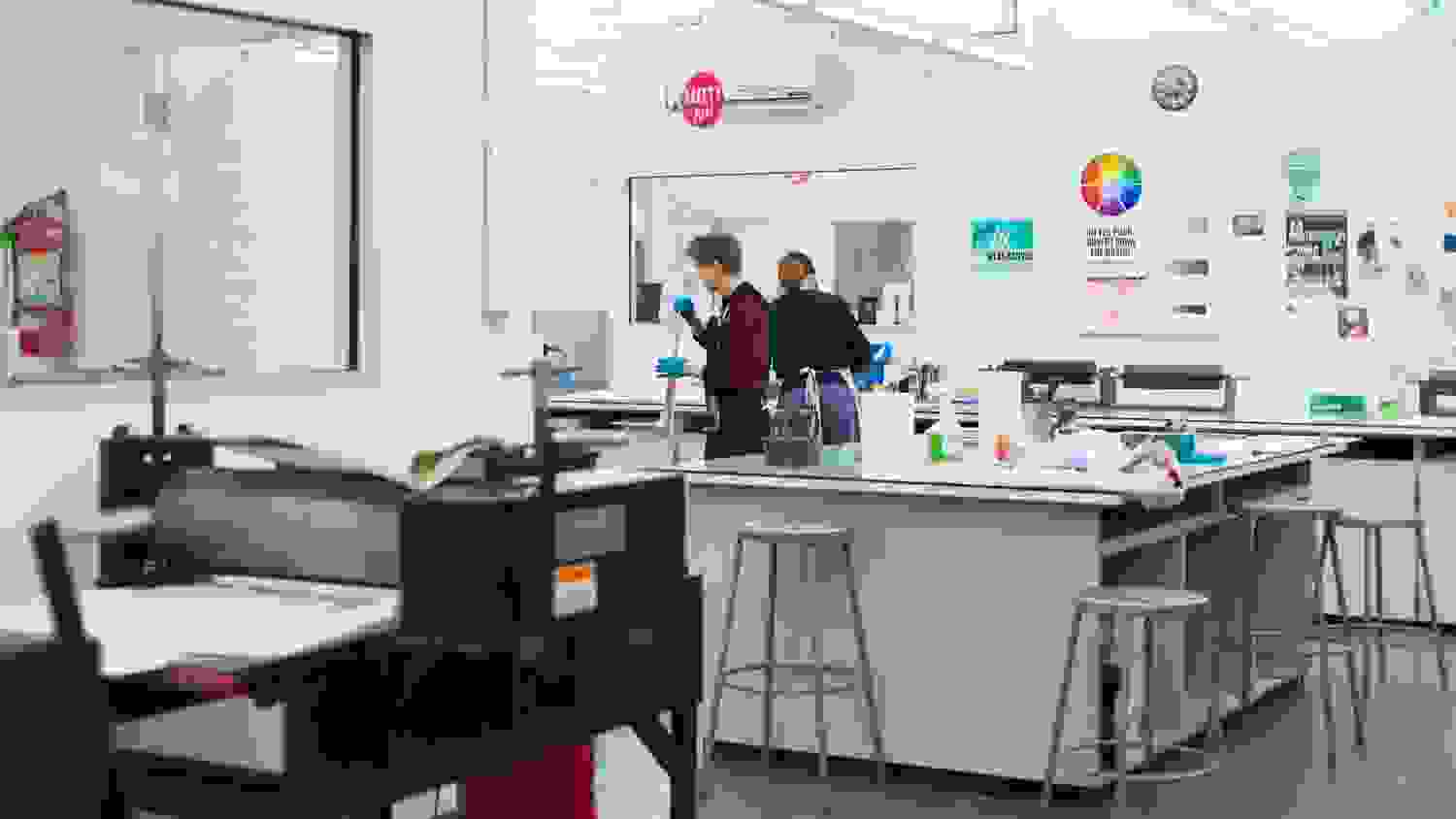Two people wearing protective latex gloves work in a printing lab