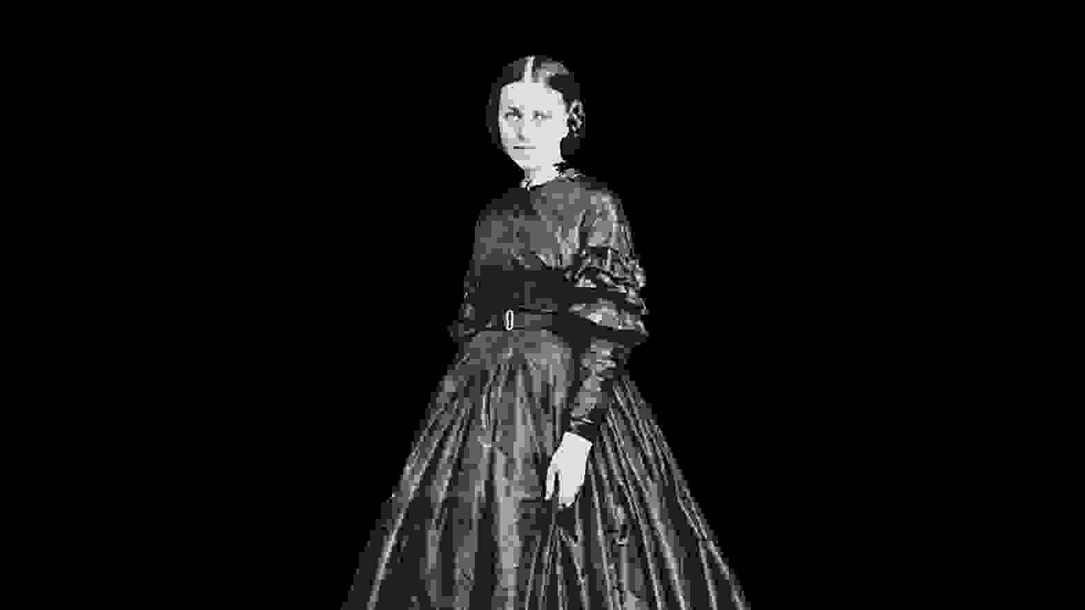 A black and white photograph of a 19th century woman against a black background.