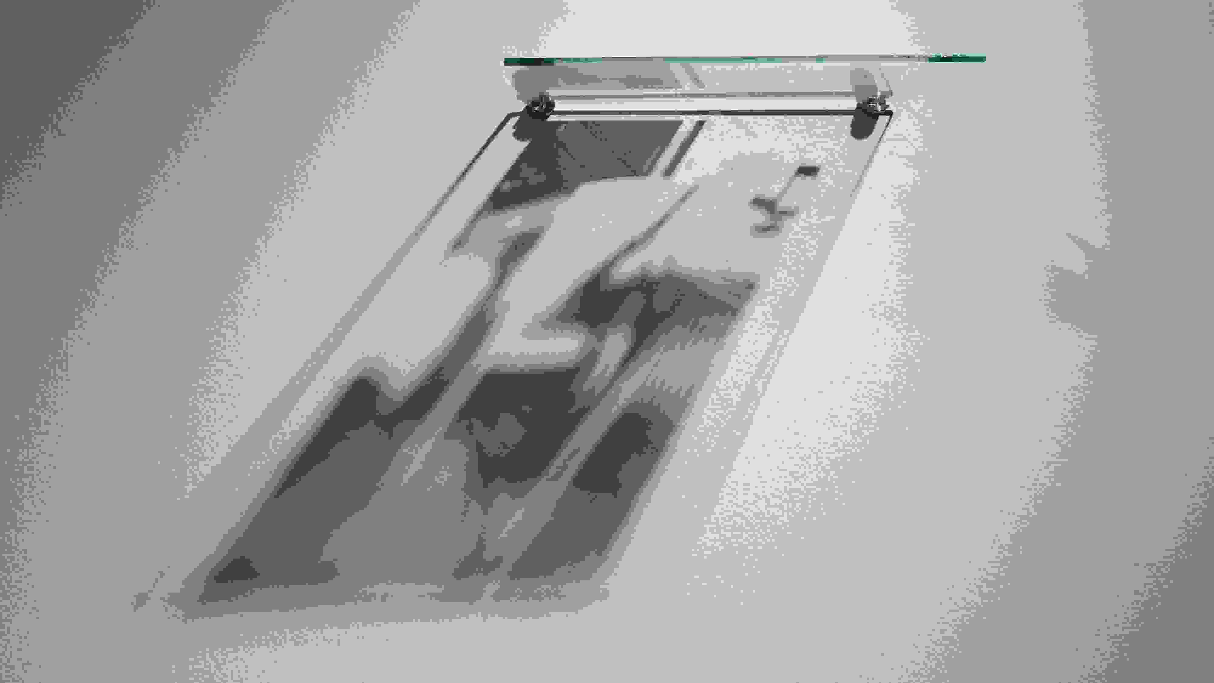 A wall-mounted, silkscreened pane of glass, lit from above, creates a shadow-based image of a lawn chair below it.