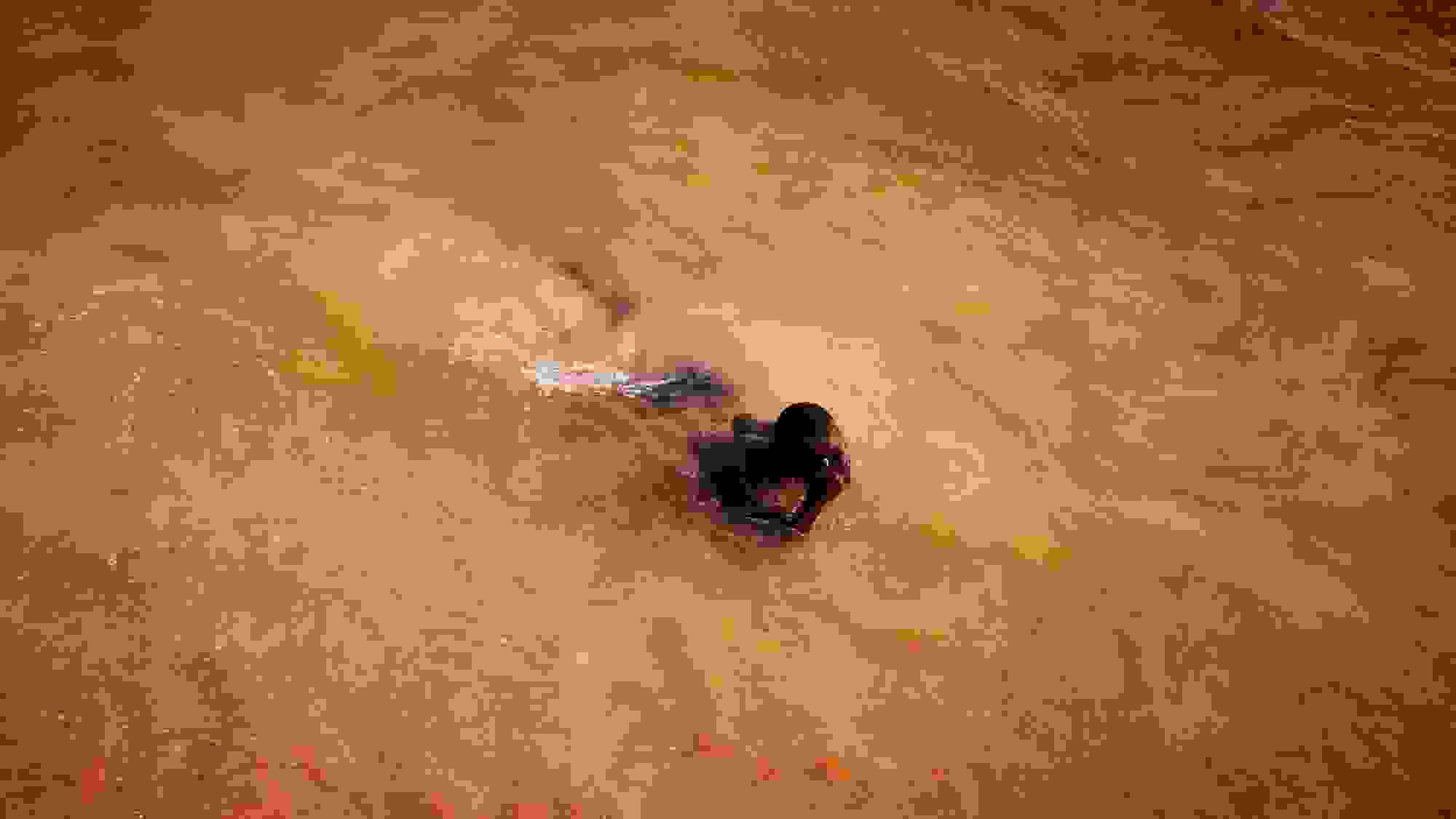 In this color photograph, a man emerges from the ocean, which has taken on a vibrant orange-ish cast in rural Saly, Senegal.