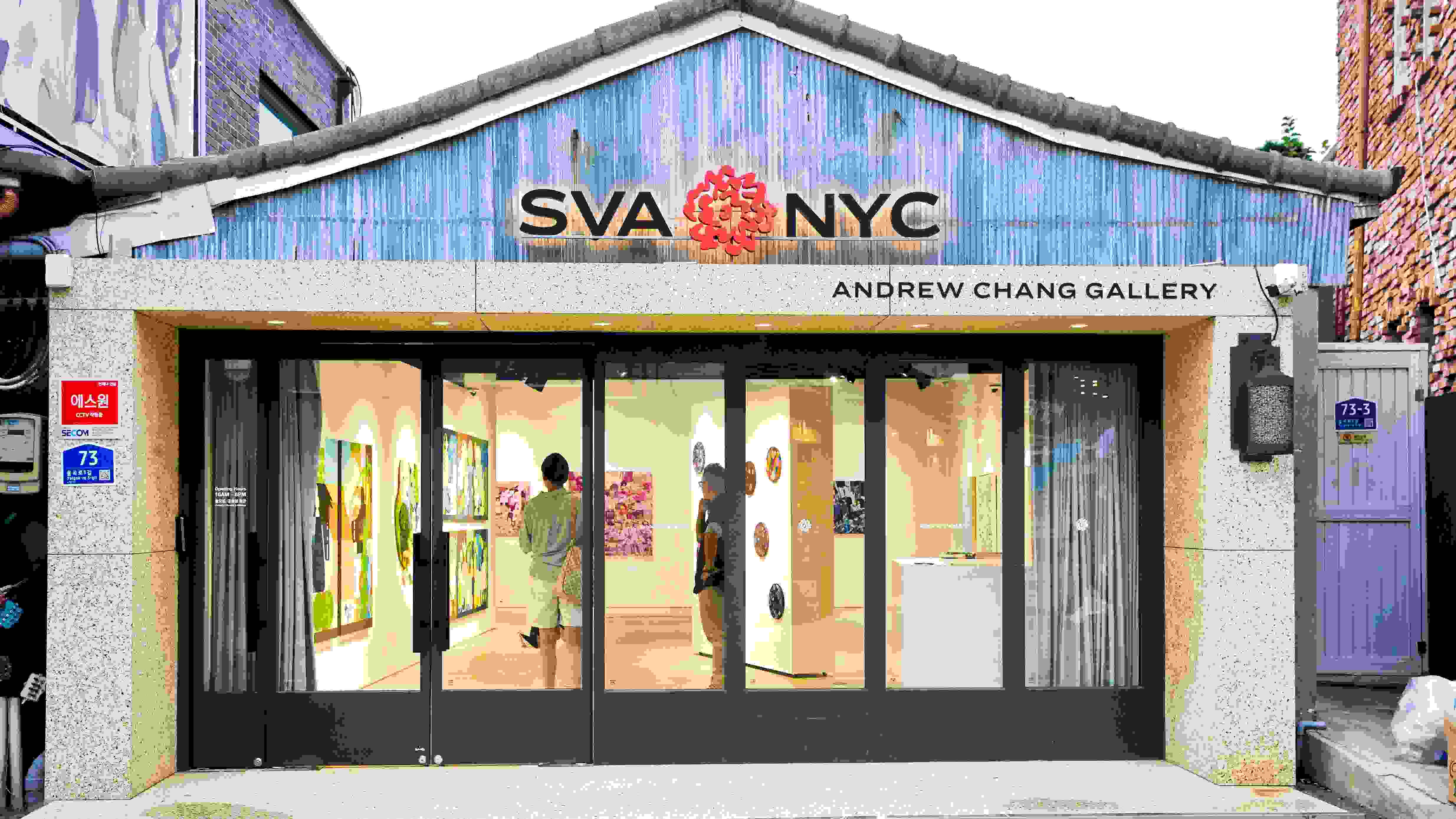 Facade of a brick and mortar gallery with "SVA NYC" insignia and red flower logo and "Andrew Chang Gallery" signs.
