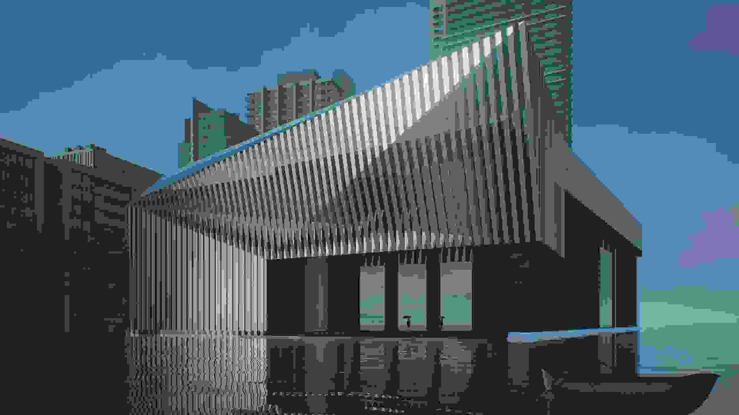 Facade of a building at dusk with a dark gray ground floor and ornamental metal awning.