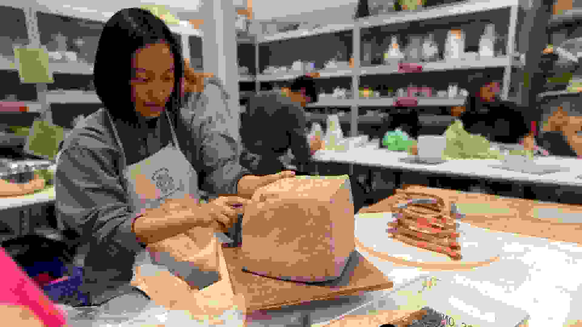 student working on a block of clay