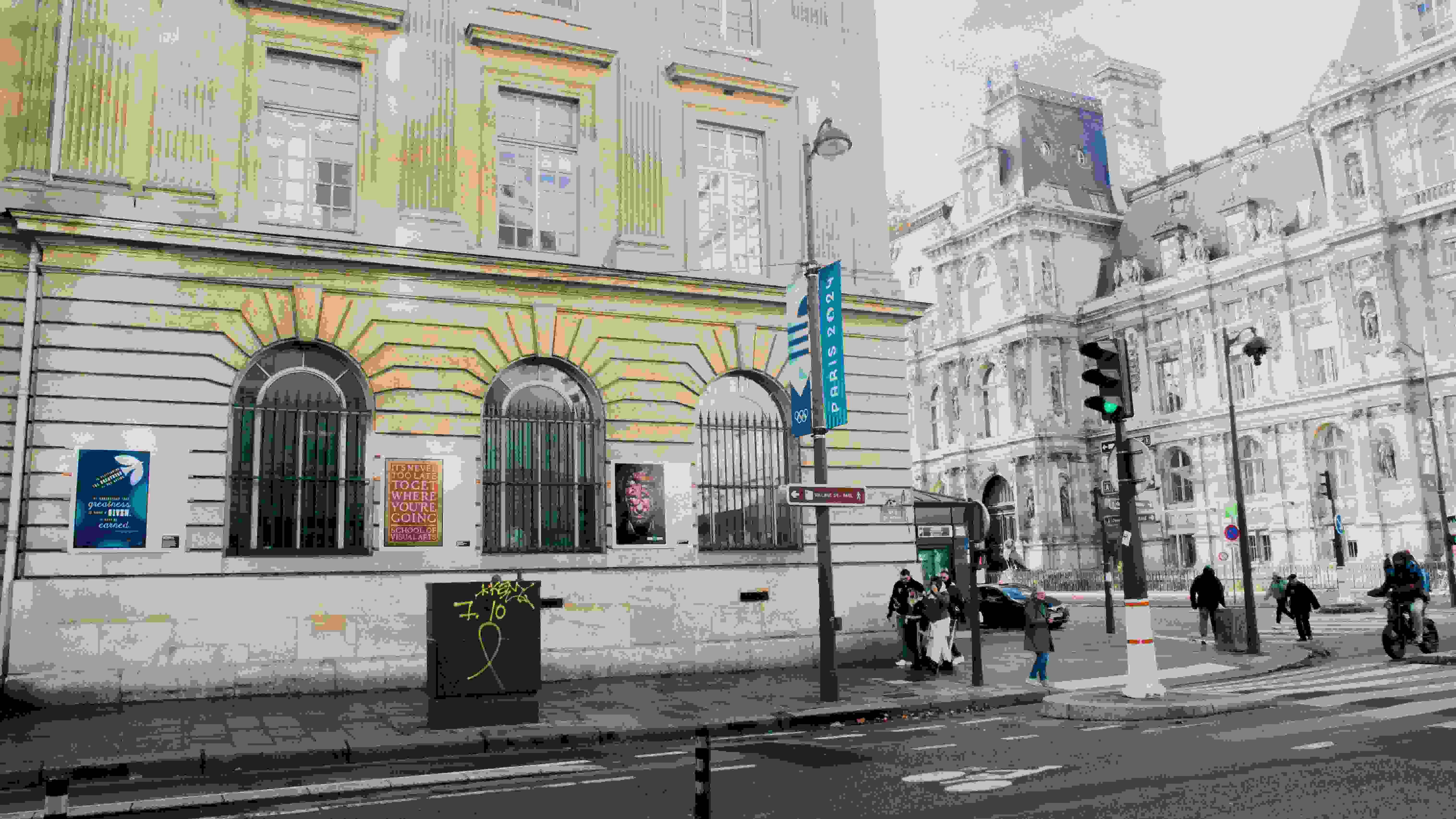 Street view of a building with SVA posters on the side. People are walking on the nearby crosswalk.