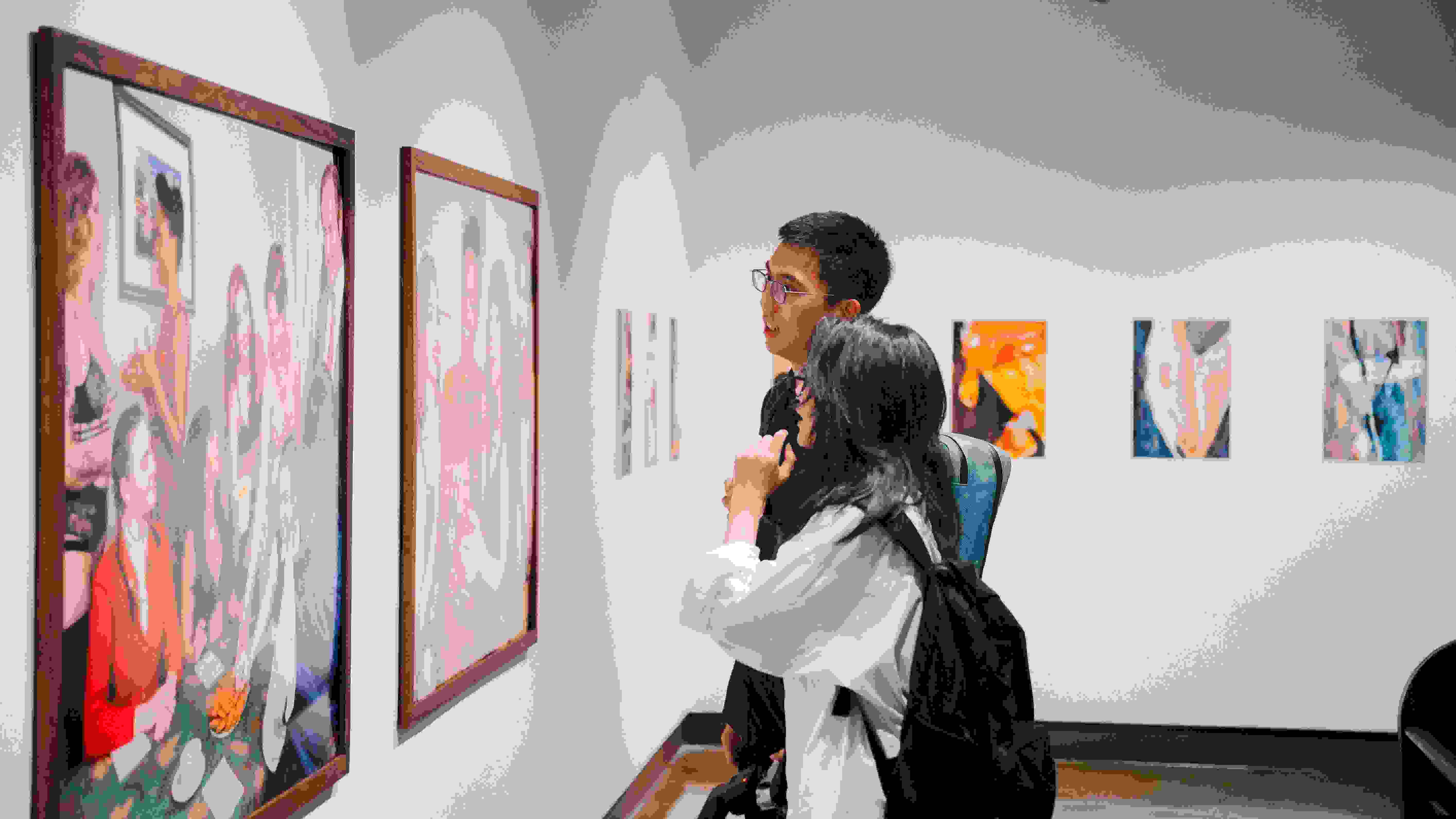 two people looking at a piece of art installed on a gallery wall