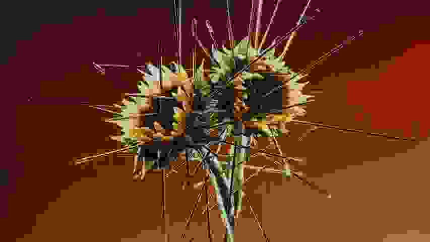 A color photograph of Two sunflowers hover mid-air, their centers skewered by dozens of sewing needles that radiate outward like spokes, set before a warm brown gradient.