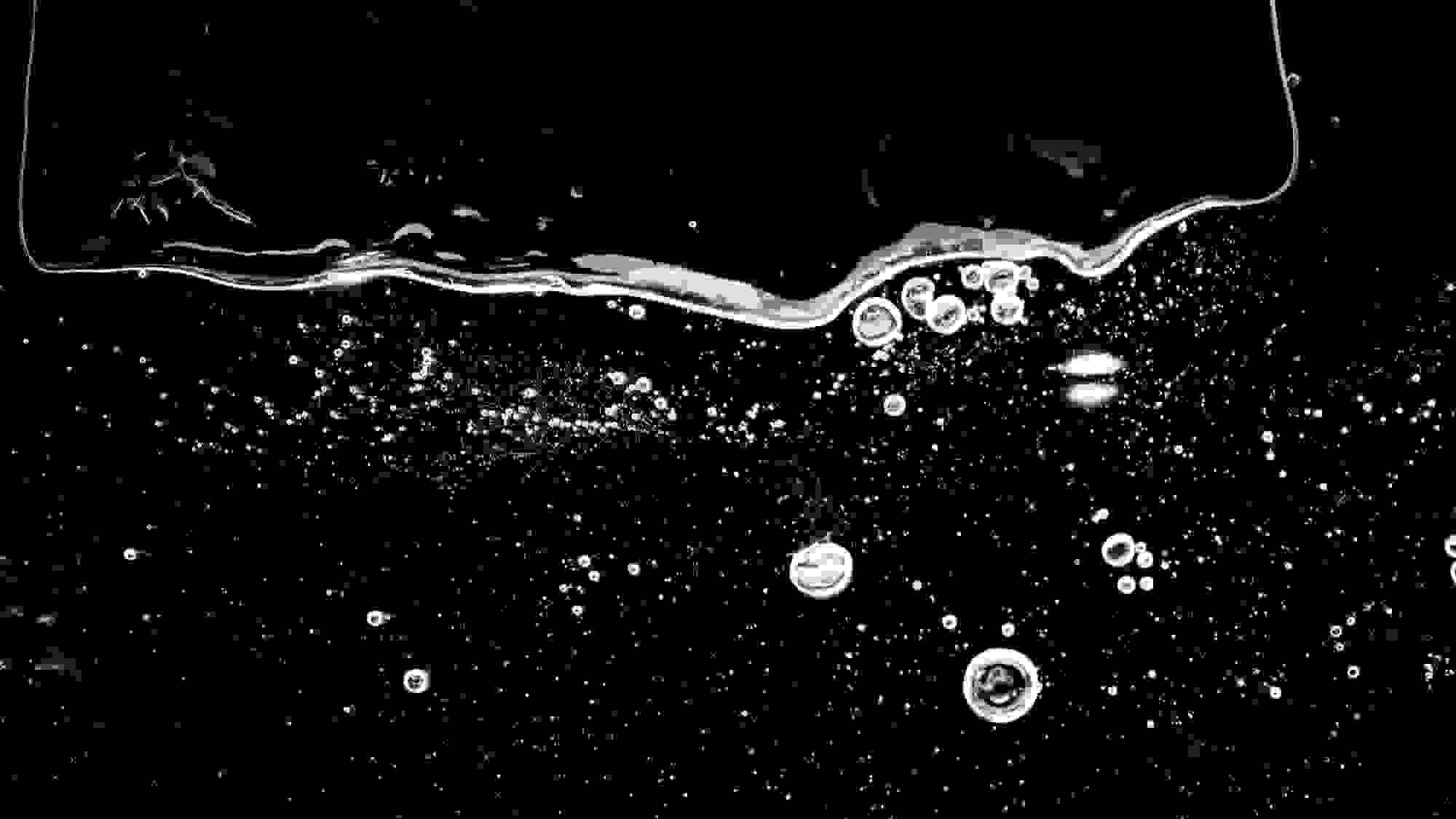 A mixed media piece of a photograph of the moon. In front of it is a piece of plexiglass where bubbles of glue have been layered to distort the image behind it.