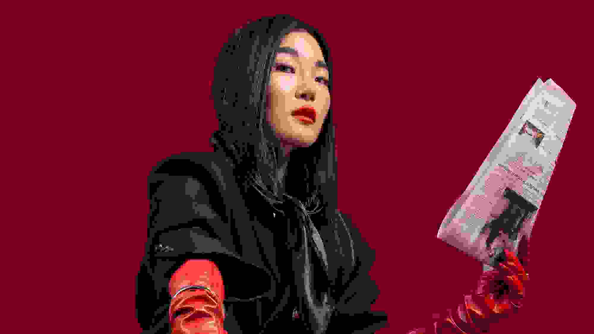 In front of the strong red solid background, the female model is wearing a matching black suit (blazer and dress pants) with black point toe heels. There are newspapers everywhere on the ground and the model is standing on it to symbolize the desire of wanting to become an important figure in the fashion (publication) industry.