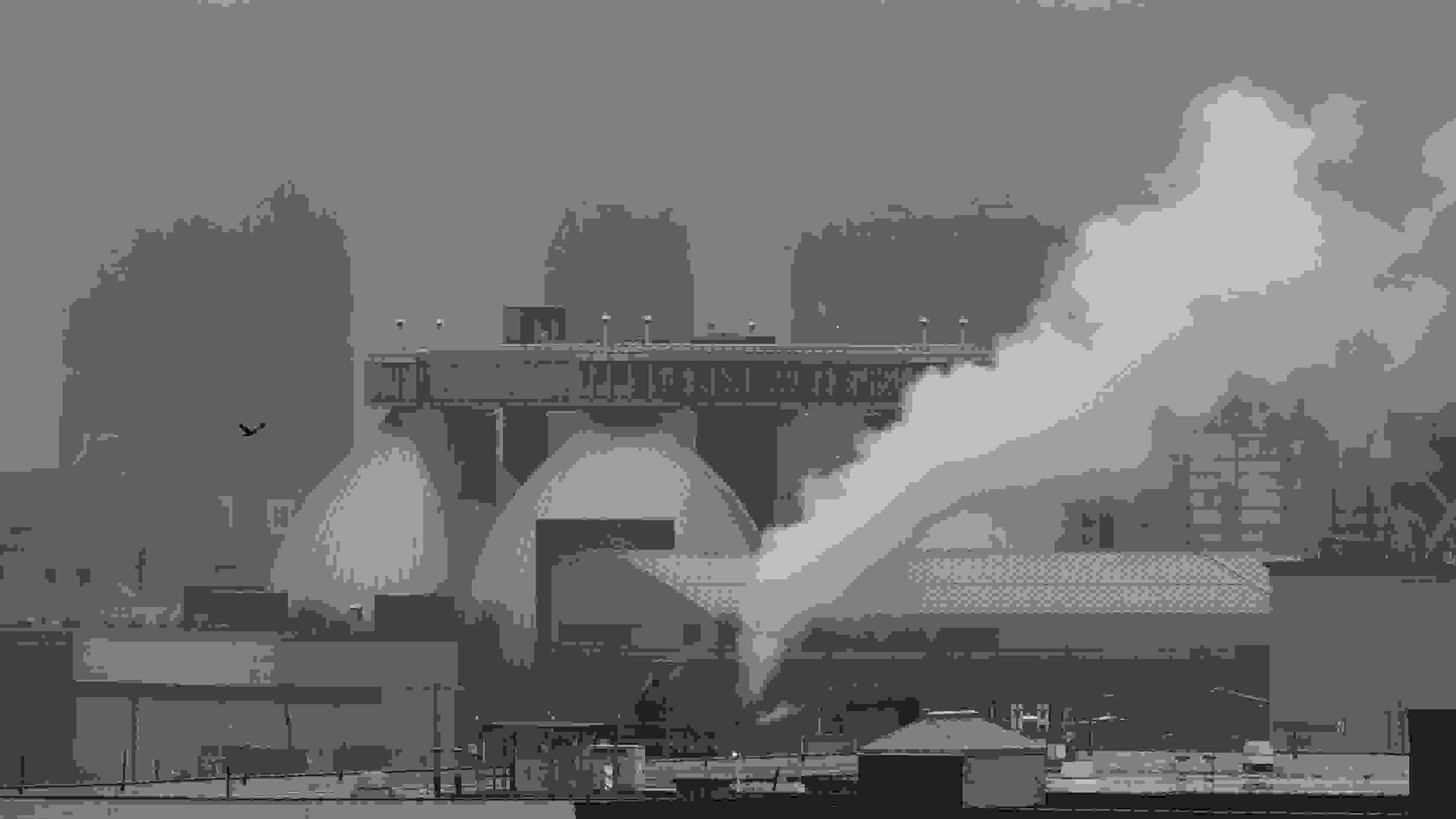 a water treatment plant with steam coming out one of its smokestacks, shot during a misty, overcast day.