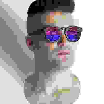 A straight-on portrait of Jon Newman wearing sunglasses with a bright, multicolor pattern in the lenses