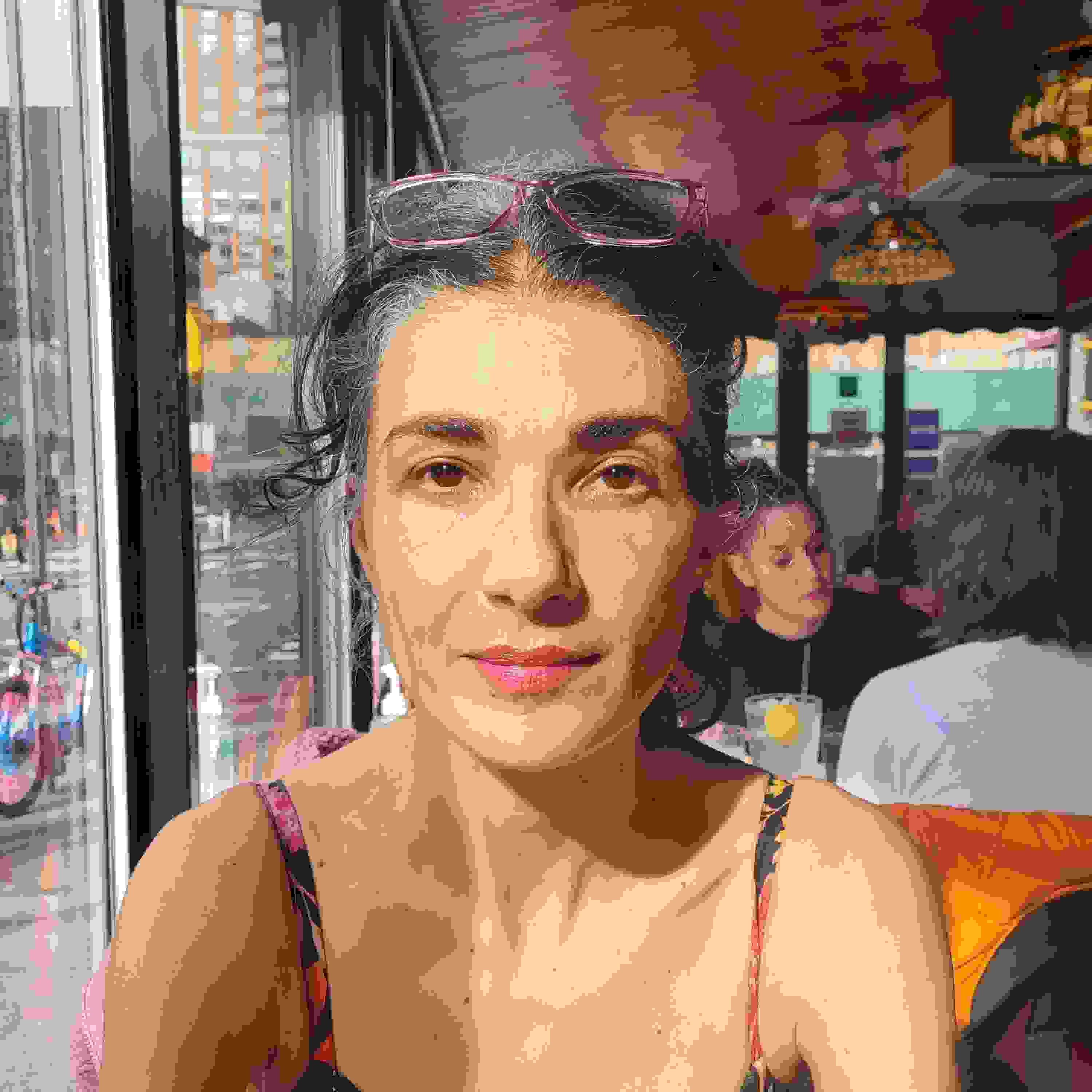 Image of a woman looking into the camera with a pair of glasses on her head.