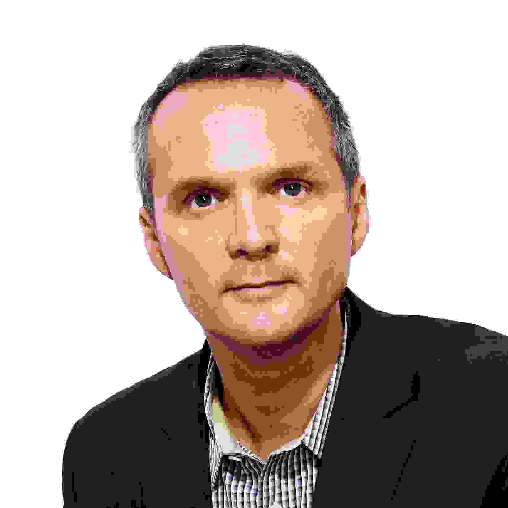 A portrait of Michael Foley, who is looking into the camera. He has light skin, is wearing a dark navy jacket over a purple and white checkered shirt, and has short brown hair. 