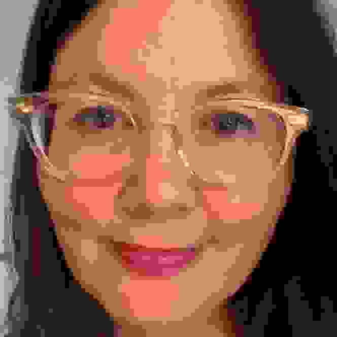 A profile picture of Laura against a white background. Laura is wearing a pair of glasses with a clear frame, and she is smiling to the camera. 