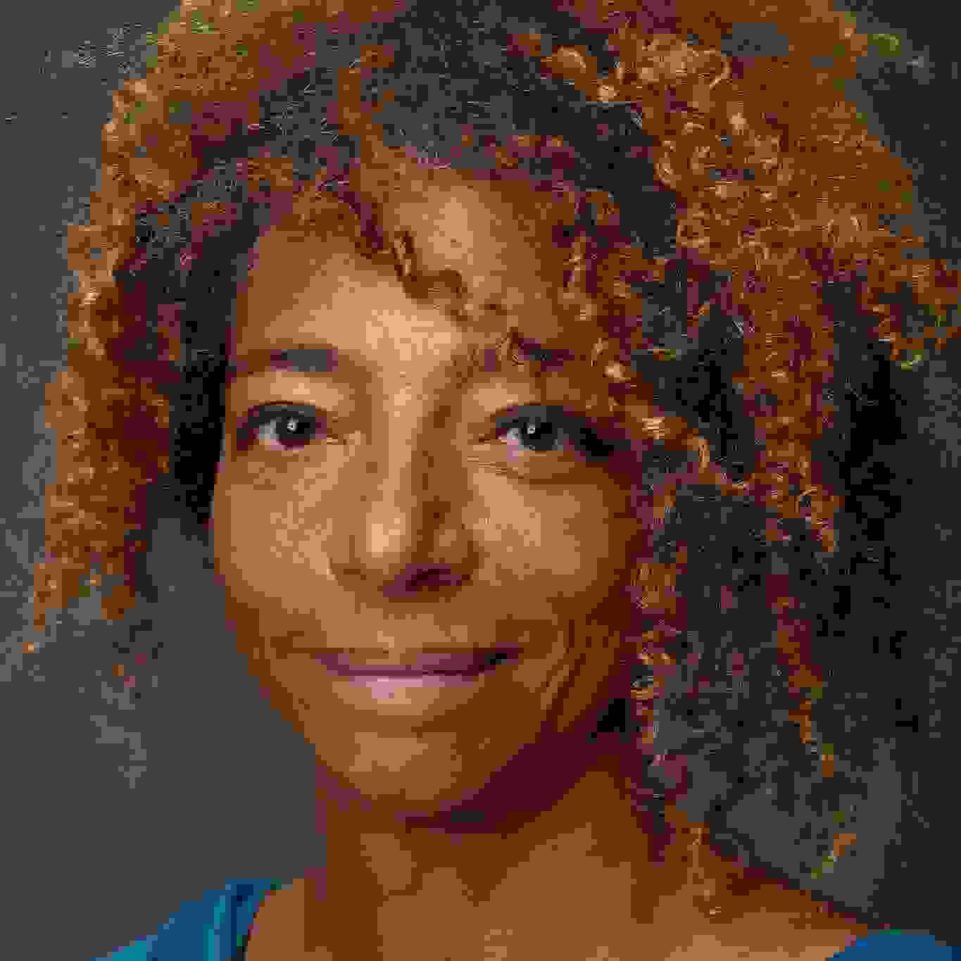 A profile photo of Samantha Isom, who is looking into the camera with a smile. She has brown skin and mid-length hair with small curls, and is wearing a blue top. 
