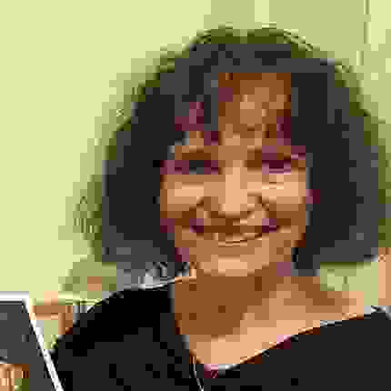 Image of Teresa Fasolino wearing a black shirt with a chain around her neck. They are smiling.