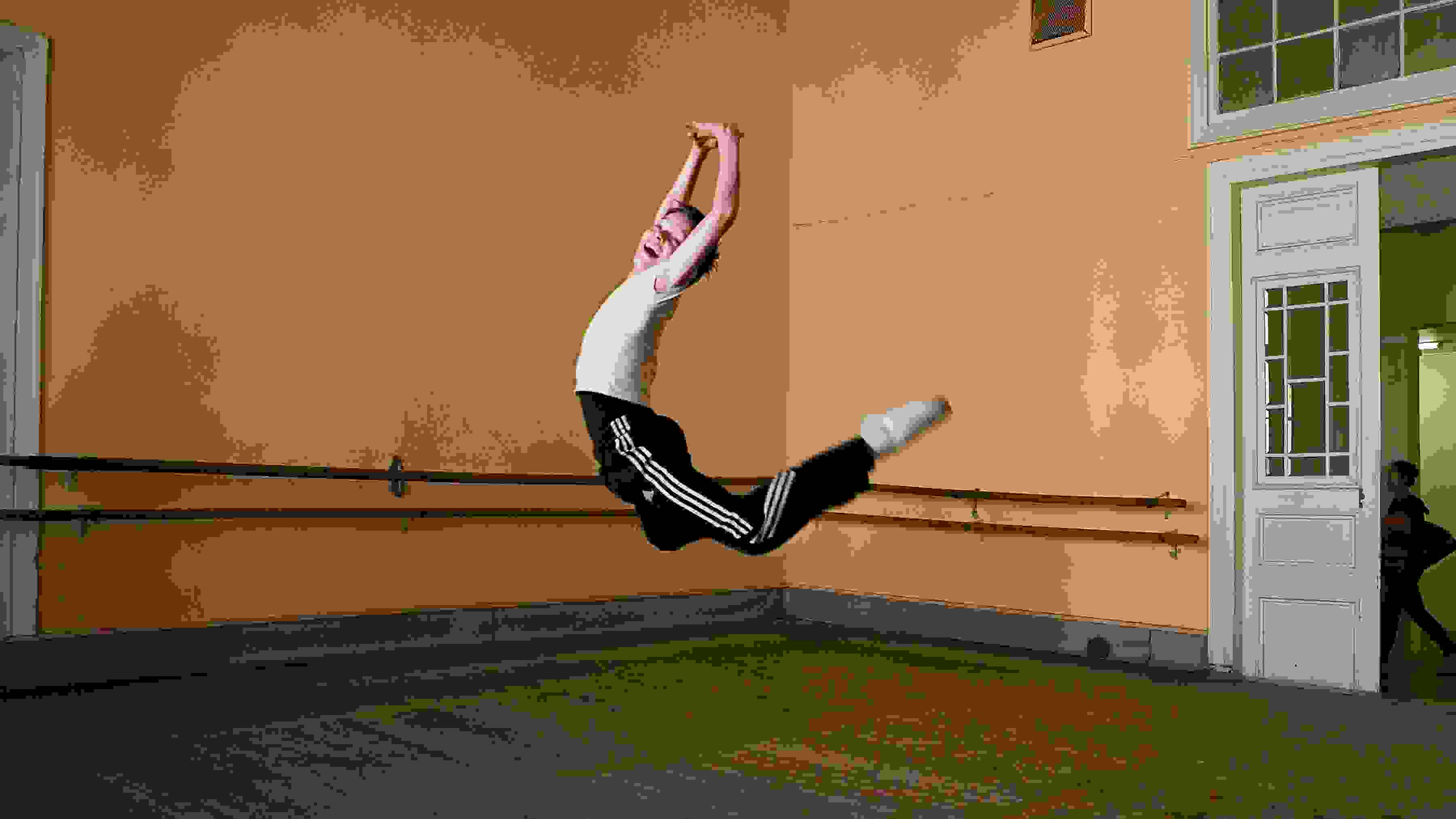Photograph of a child leaping into the air in a ballet classroom.