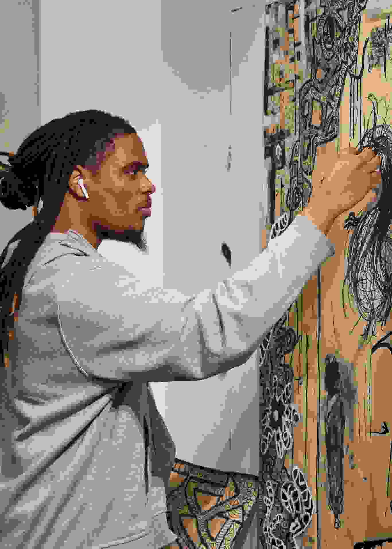 A person in a gray hoodie wearing air pods works on a wall mural