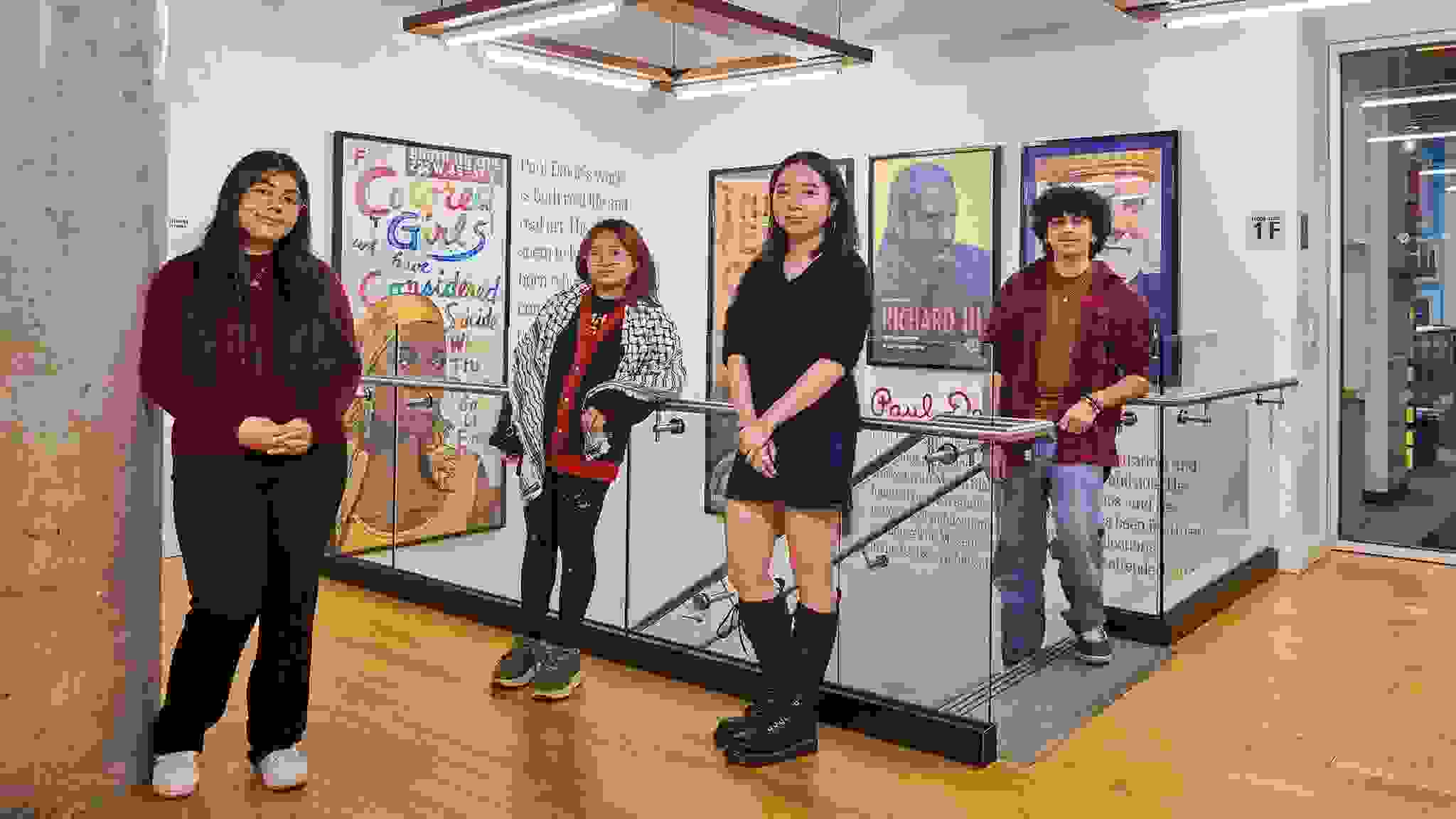 A group of students pose for a photo in an undergraduate admissions facility with bright colored posters on the wall.