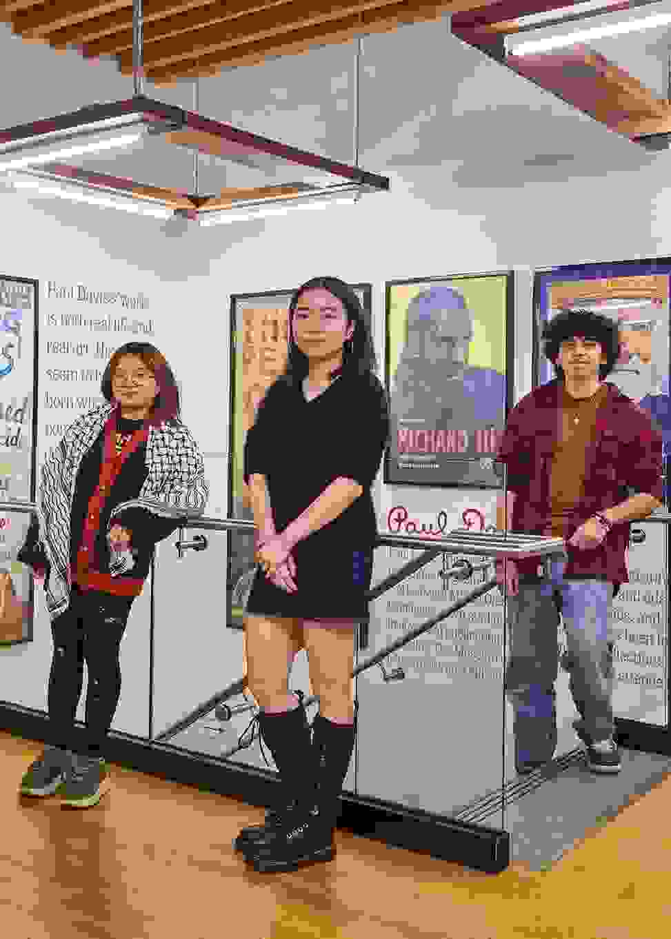 A group of students pose for a photo in an undergraduate admissions facility with bright colored posters on the wall.