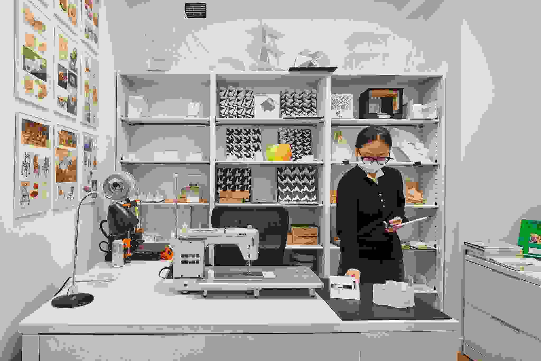 Student arranging their workspace in a maker lab furnished with a sewing machine and textile samples.