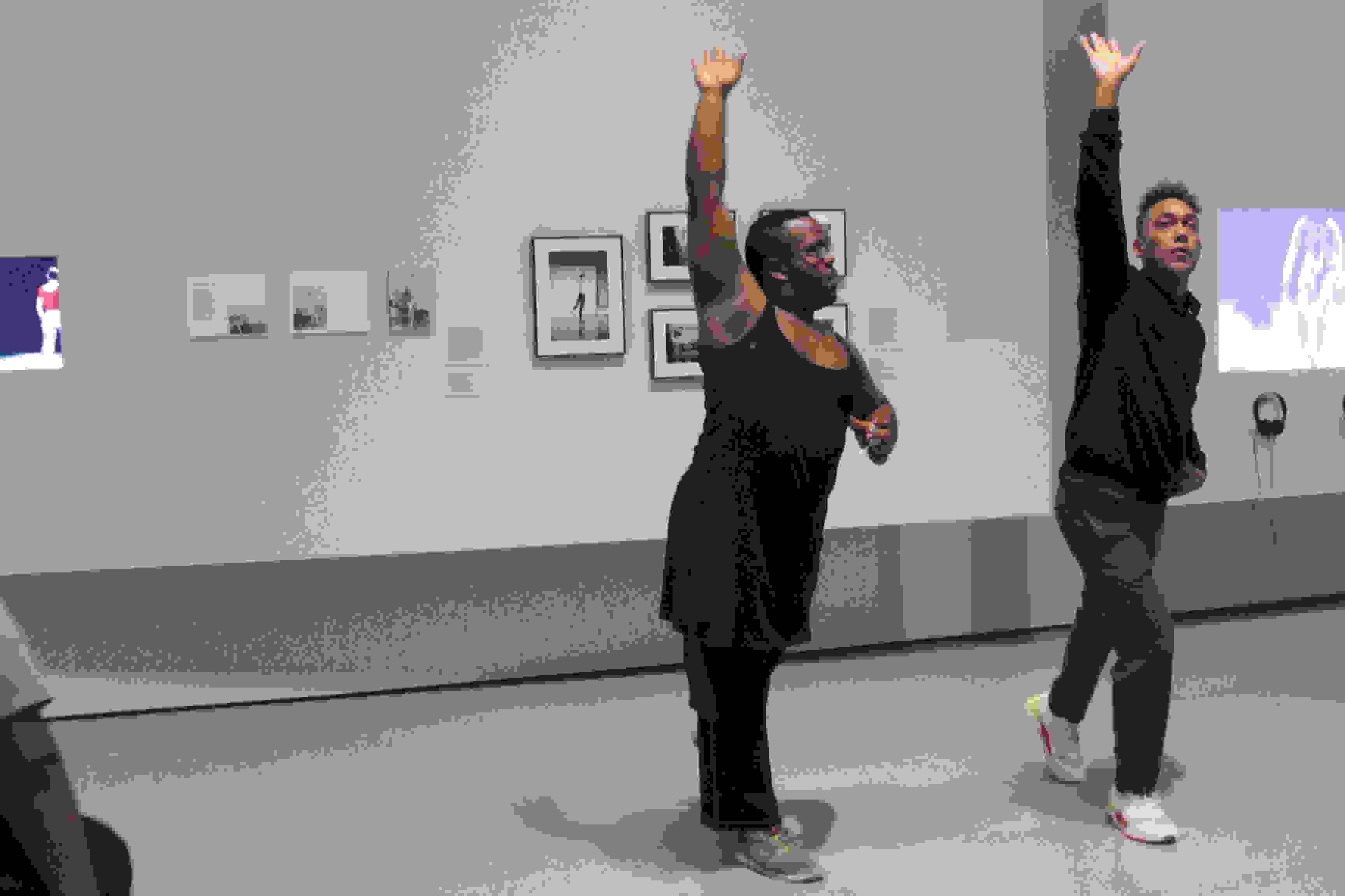 <p "="">Two people stand next to each other, their actions mirroring each other—right foot in front and right arm raised, with palm upward.