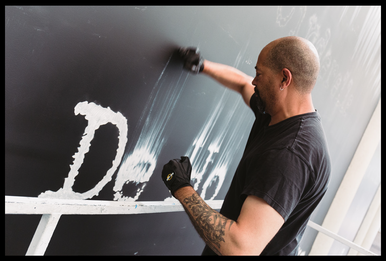 <p "="">Artist Gary Simmons uses his fists to smudge the wet paint of white letters on a black wall.