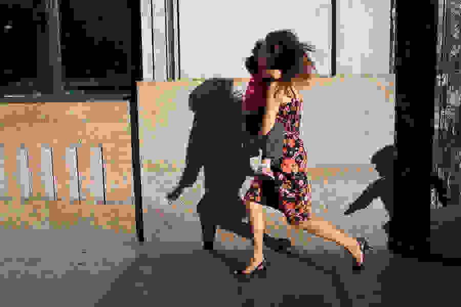 A woman holding a child and being chased down the street (as seen in the shadow). The woman is wearing a floral dress and black heels.