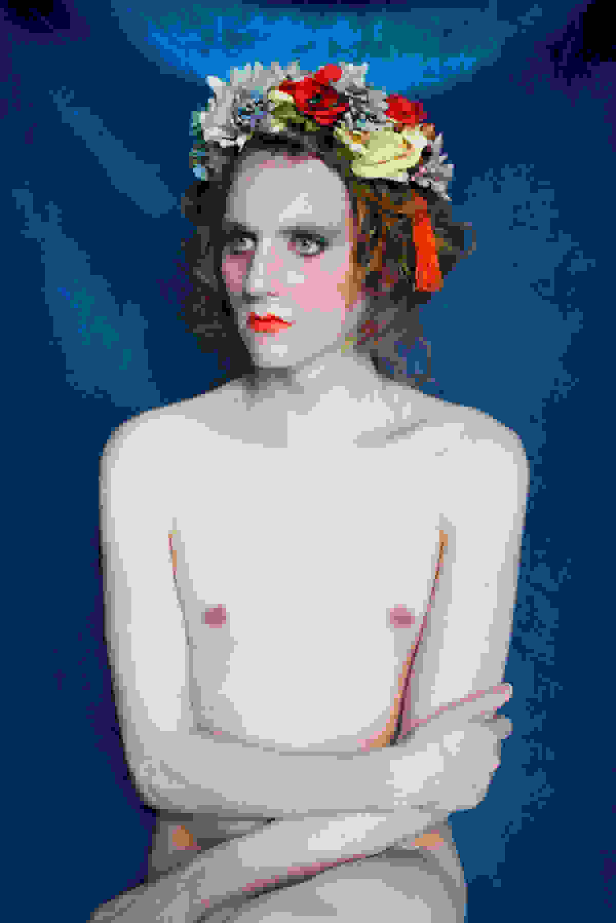 <p "="">A photograph of a person sitting with legs and arms crossed and wearing a floral headband.