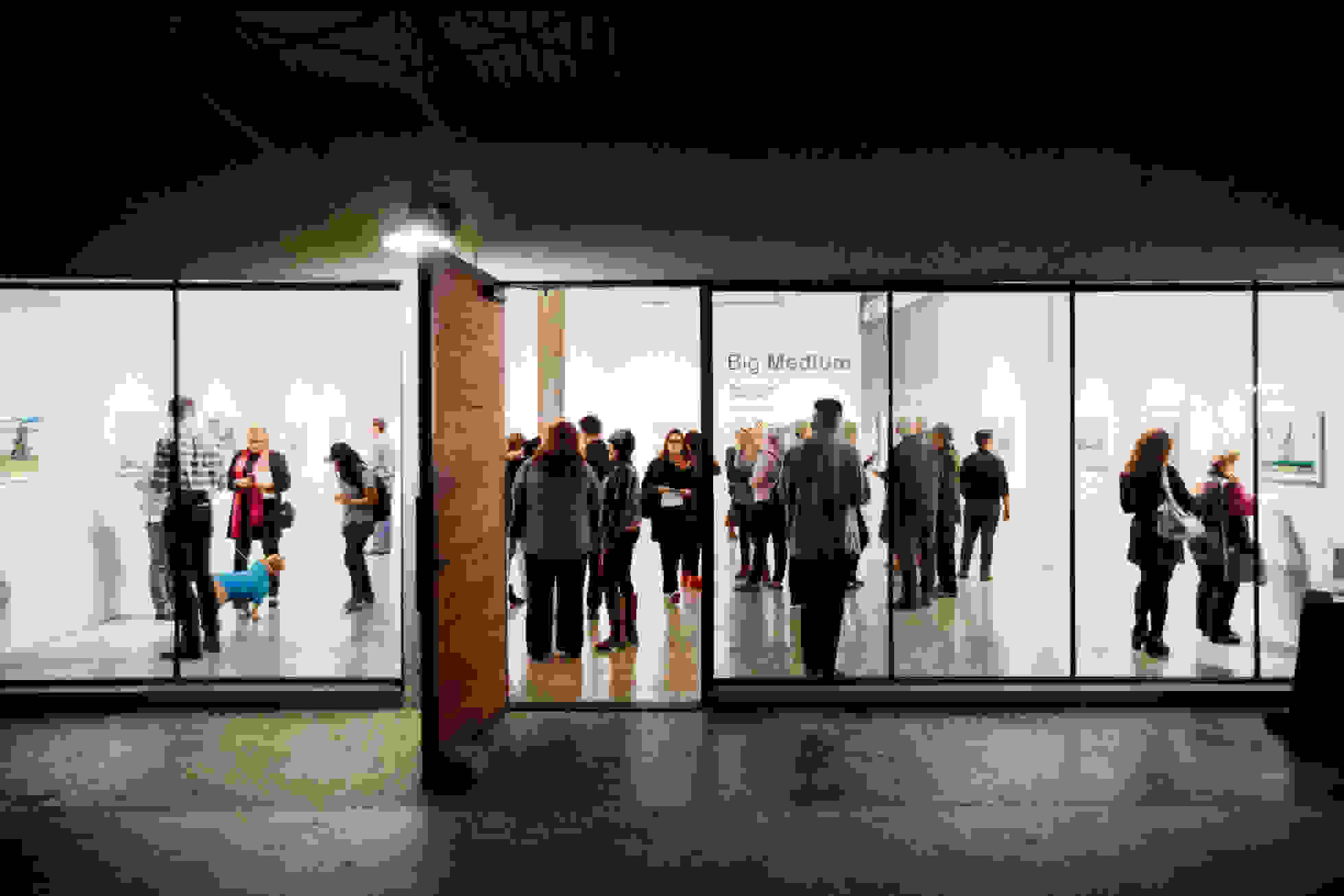 Dimly lit hallway outside of a busy art exhibition