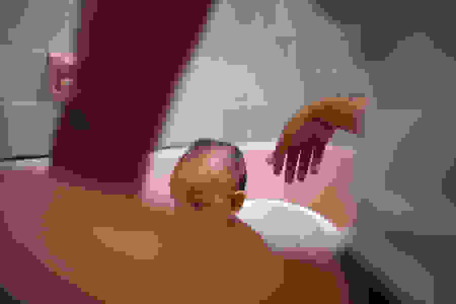 Washing infant in the bath.