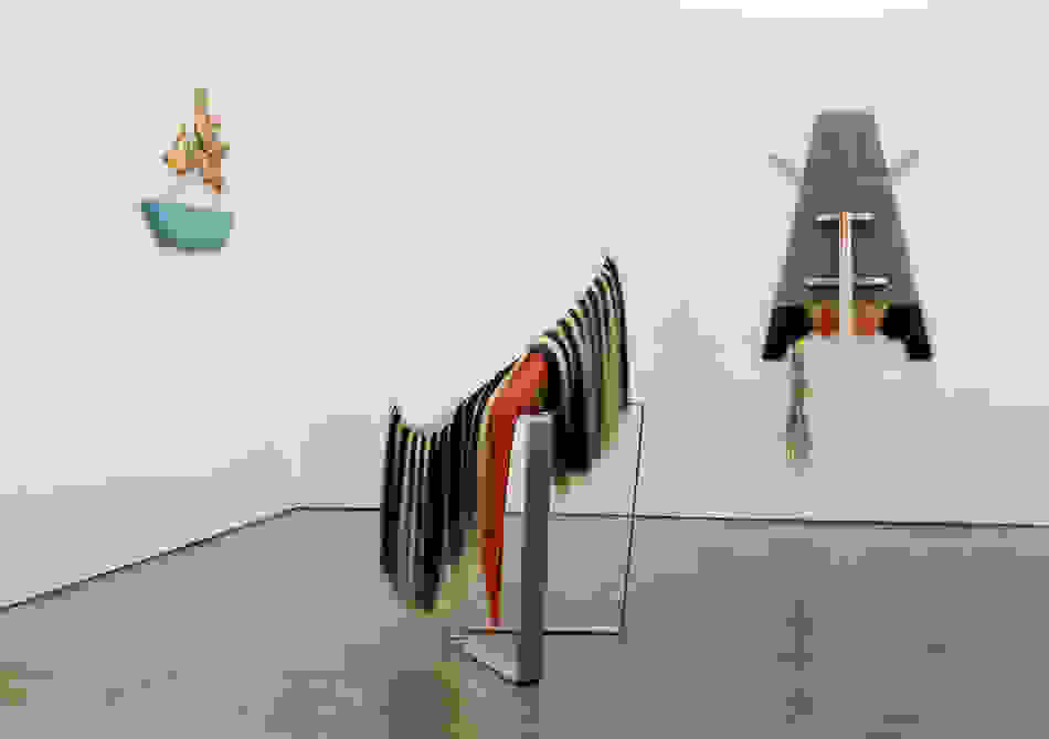<p "="">An installation view of three fabric-based sculptures—two hung on adjacent gallery walls and one tilting on a metal stand on the concrete floor.