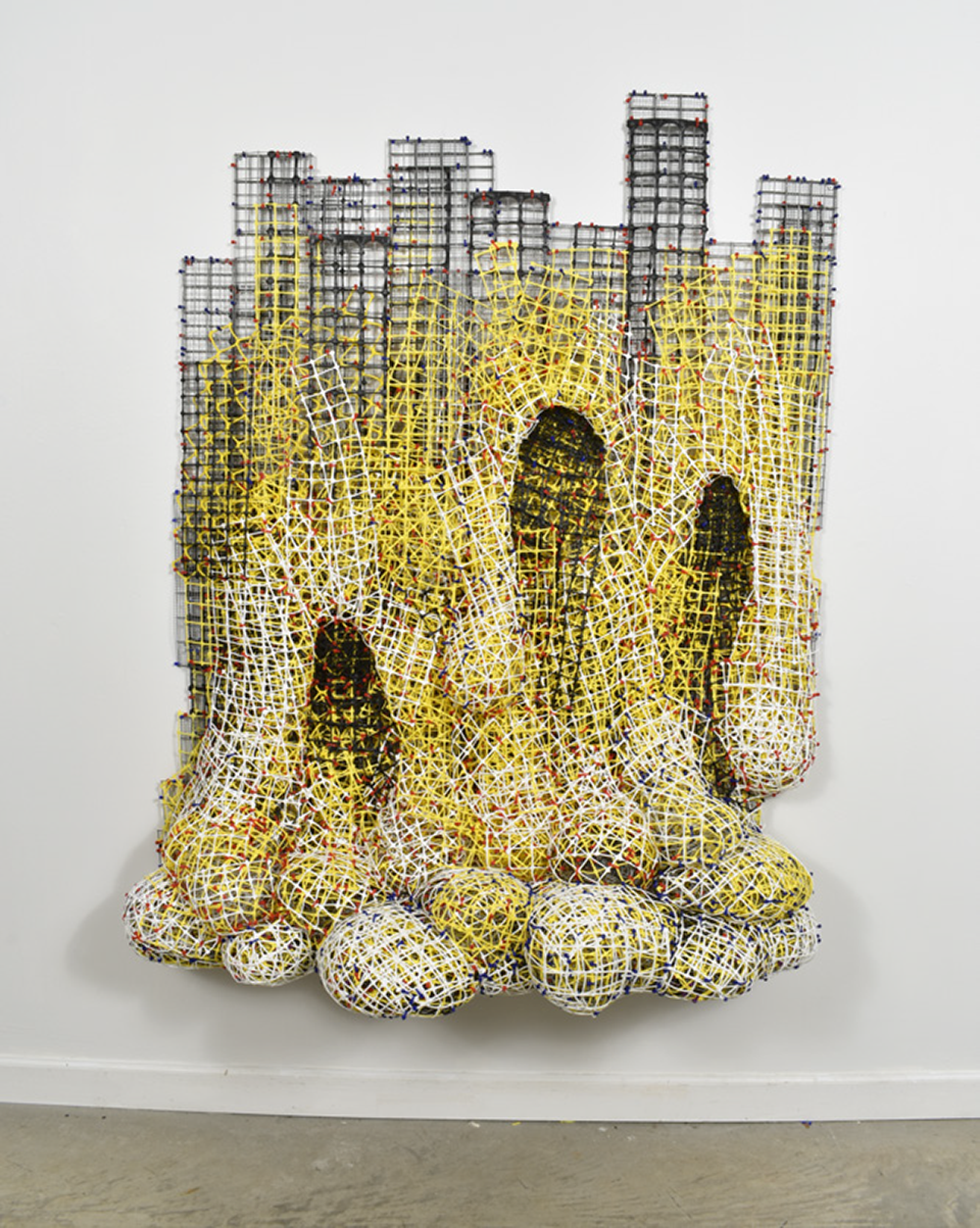 <p "="">A wall-mounted abstract sculpture made of yellow, black and white fence material.