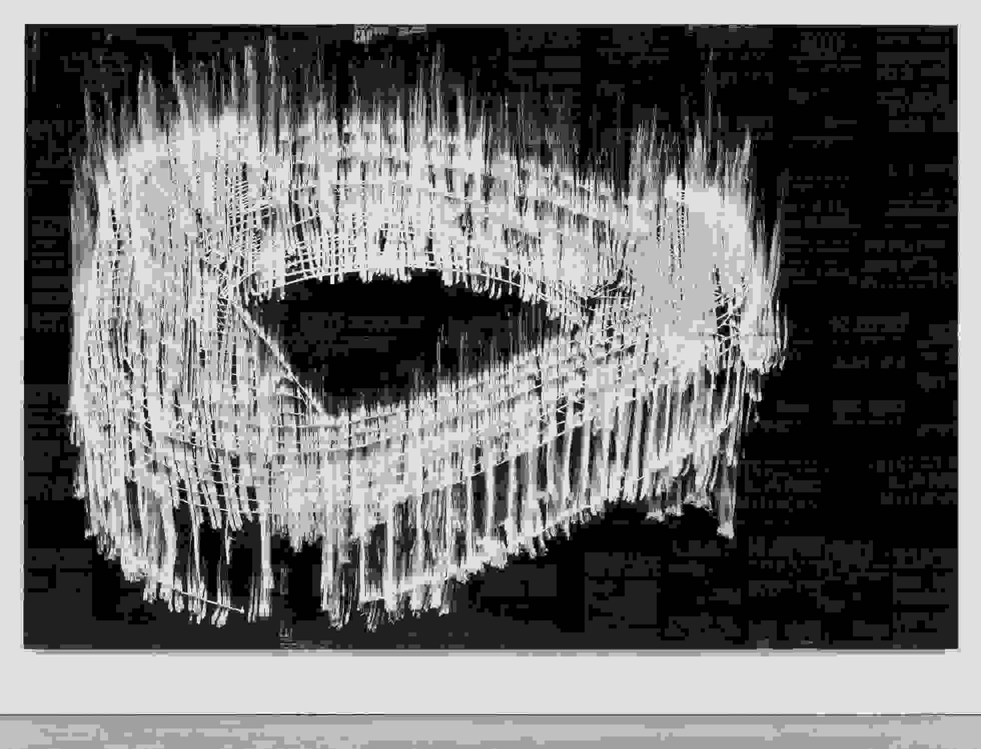 <p "="">A large monochrome painting of a stadium, done on a collage of dark-hued reproductions of boxing posters.