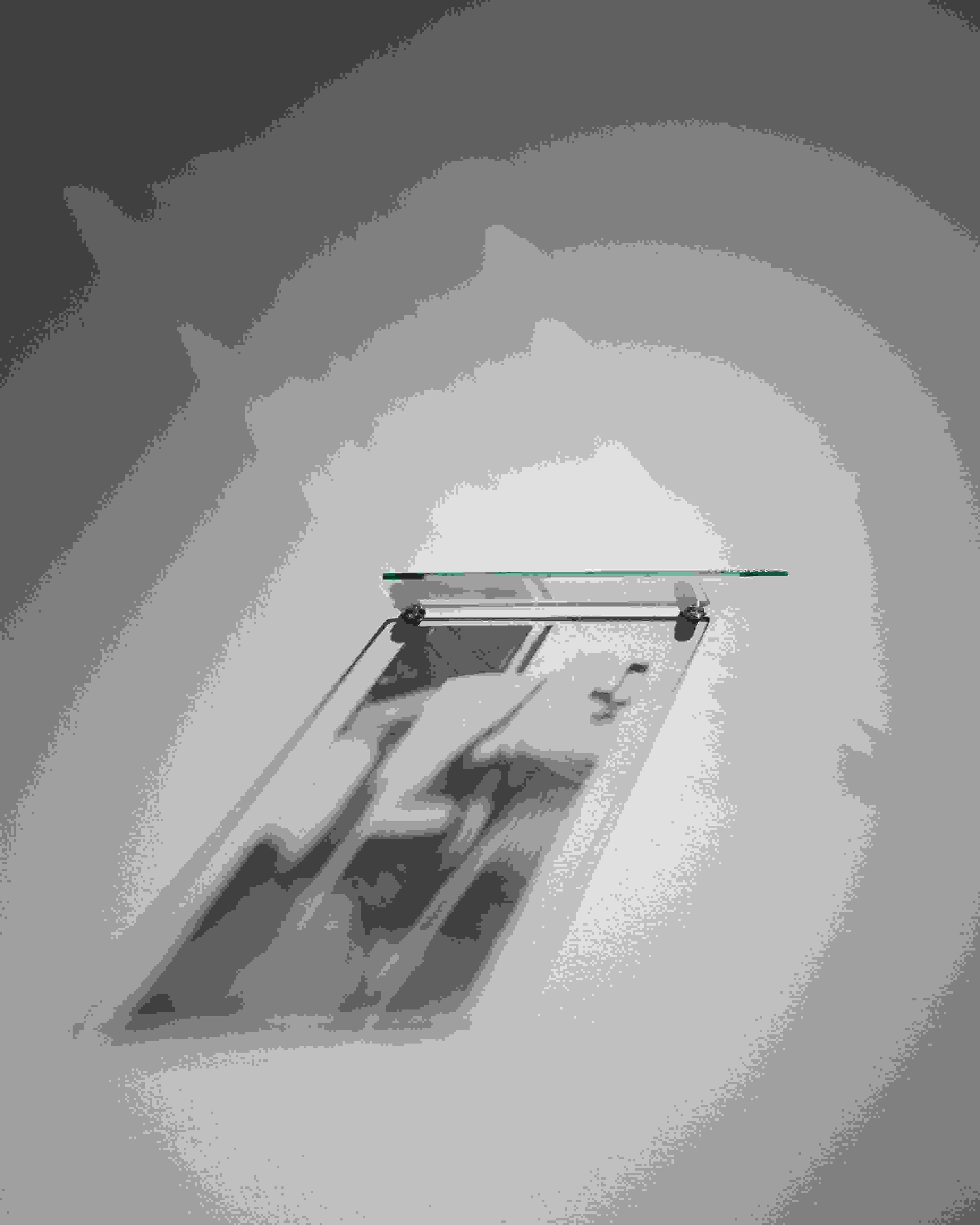 A wall-mounted, silkscreened pane of glass, lit from above, creates a shadow-based image of a lawn chair below it.