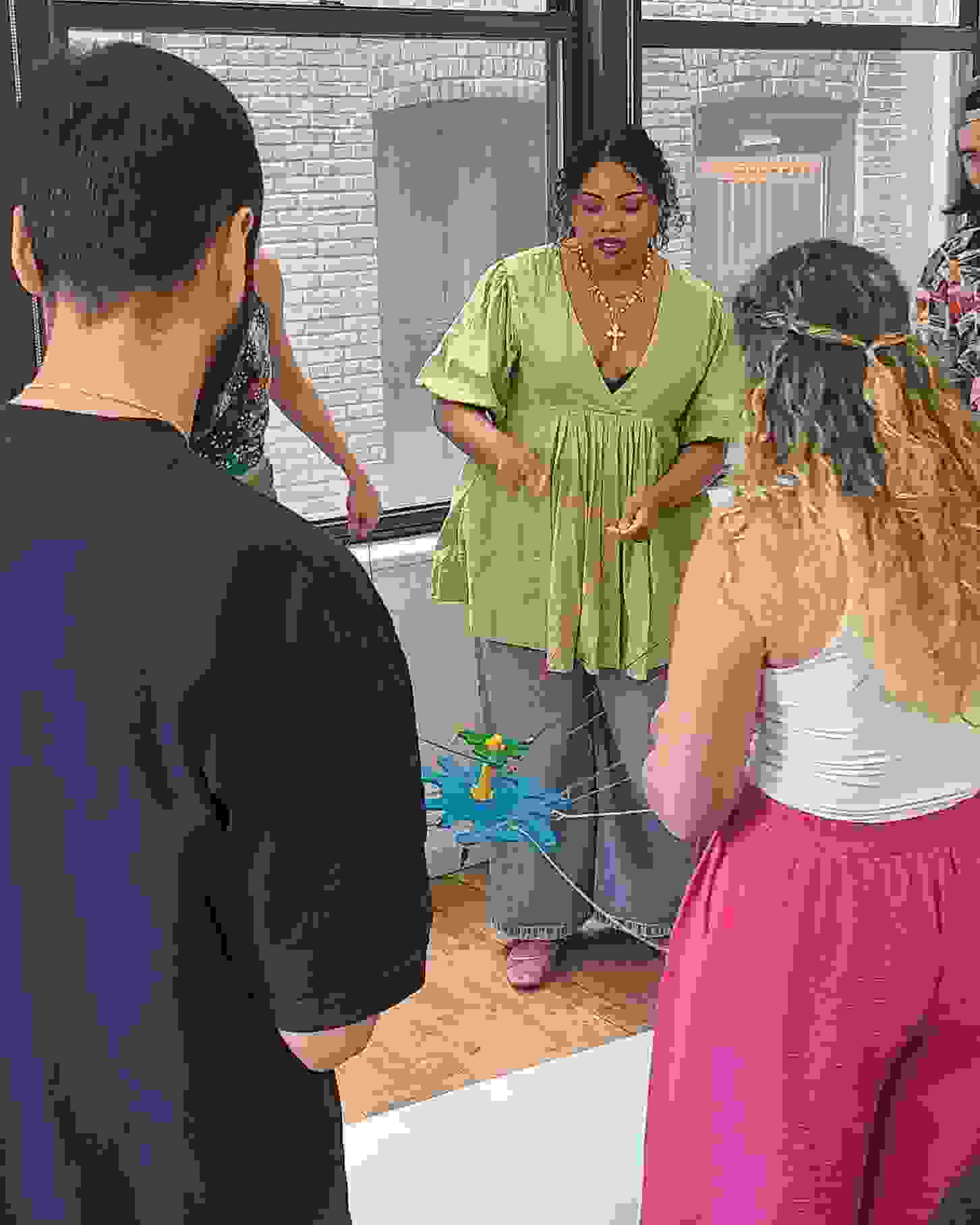 Students working together with string to control a pen over paper.