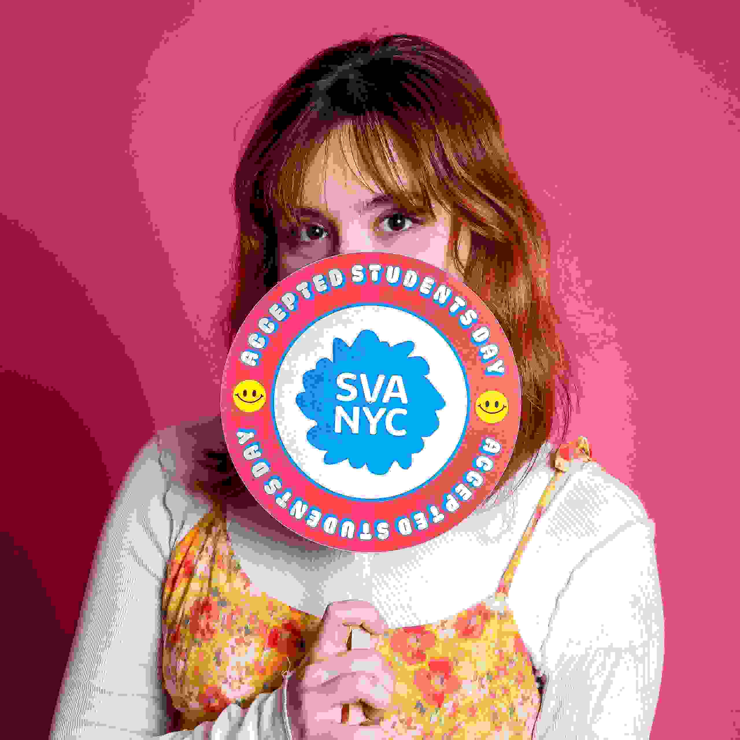 A person poses with a sign reading SVA NYC Accepted Students Day in front of a pink background