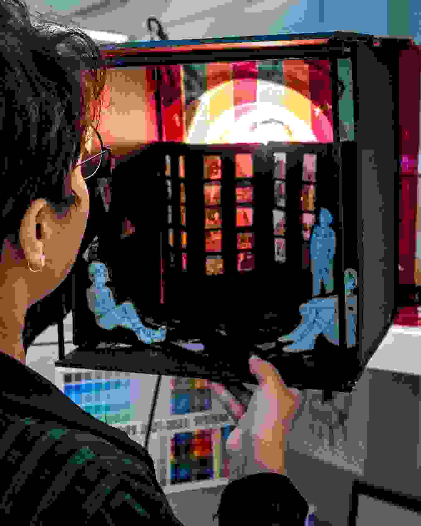 Photo of person holding a box containing a diorama that is illuminated, in the studio of MFA Visual Narrative's summer studio's