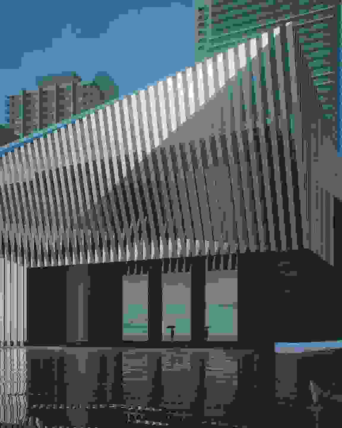 Facade of a building at dusk with a dark gray ground floor and ornamental metal awning.