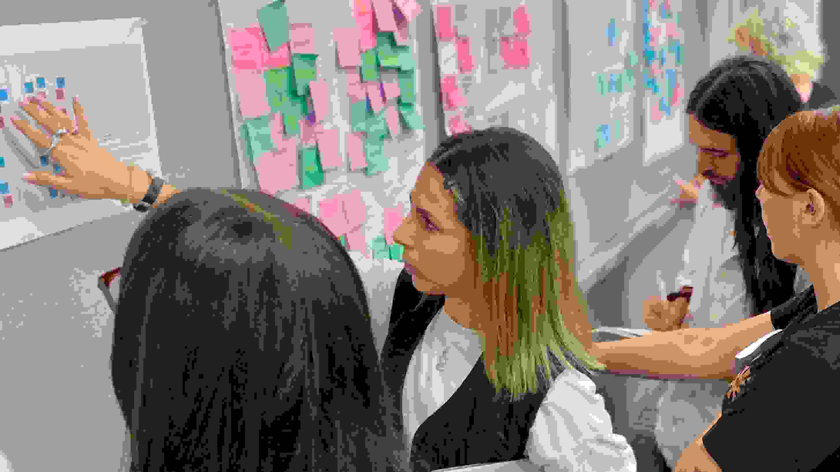 A group of students critiquing presentations that are hung up on the wall.