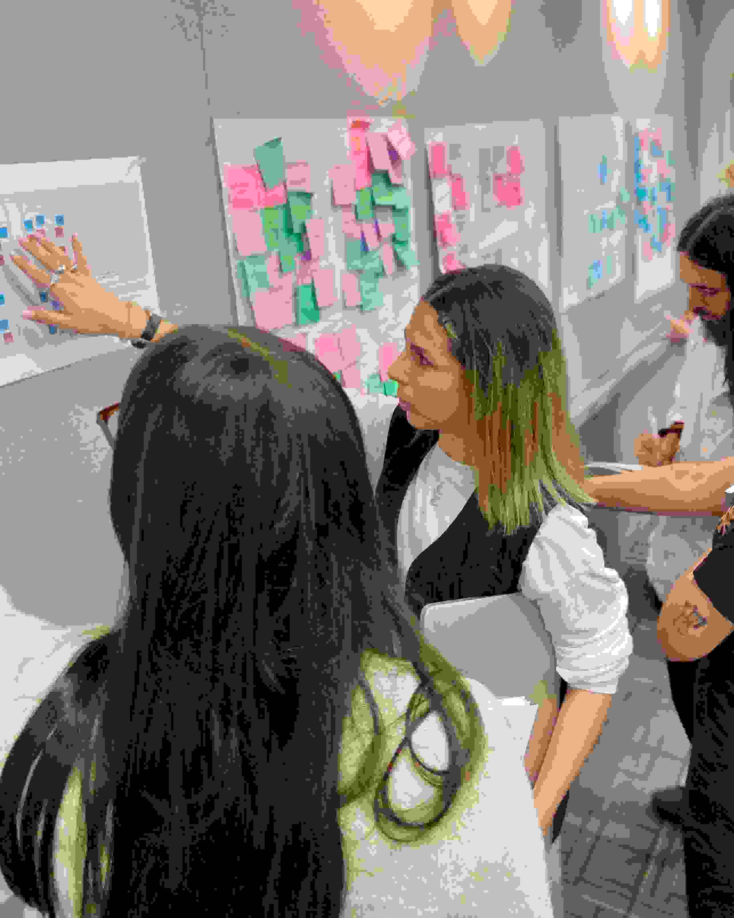 A group of students critiquing presentations that are hung up on the wall.