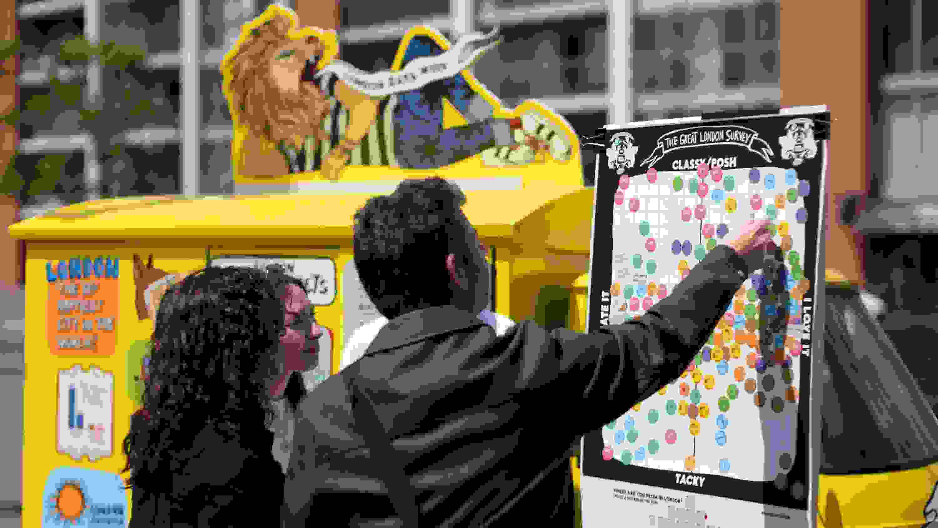 A small group of people adding stickers to a poster labeled The Great London Survey by Data Vandals