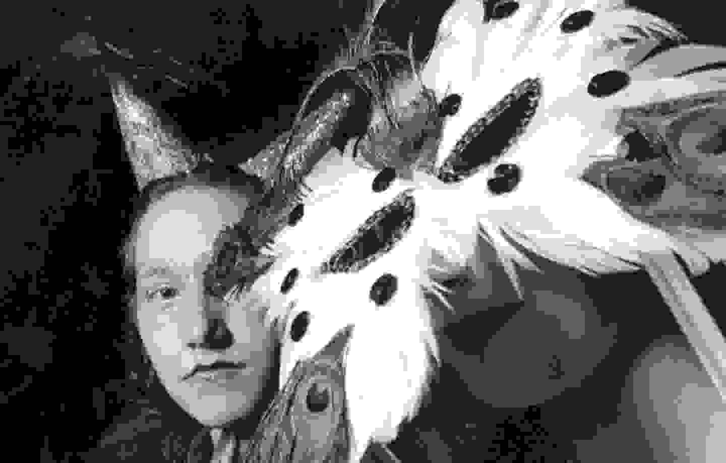 Black and white close up crop of people in Venetian type masks and headpieces with glitter makeup